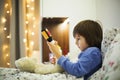 Cute sick child, boy, staying in bed, playing with teddy bear Royalty Free Stock Photo