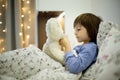 Cute sick child, boy, staying in bed, playing with teddy bear Royalty Free Stock Photo