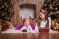 Cute sisters lying near christmas trees