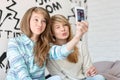 Cute sisters pouting while taking photos with smart phone at home Royalty Free Stock Photo