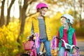 Cute sisters riding bikes in a city park on sunny autumn day. Active family leisure with kids. Children wearing safety hemet while Royalty Free Stock Photo