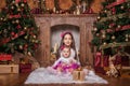 Cute sisters sitting near christmas trees