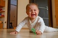 Cute six months old baby boy having tummy time on the floor and crying for attention Royalty Free Stock Photo