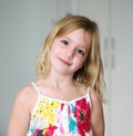 Six year old blonde girl in a summer white dress with flowers smiling on an abstract background Royalty Free Stock Photo