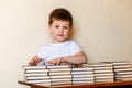 Cute six-year-old boy sitting at a Desk with stacks of books Royalty Free Stock Photo