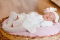 Cute sleeping baby girl in smart white dress and golfs lies on a round crib. photo shoot of newborns Royalty Free Stock Photo