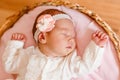 Cute sleeping baby girl in smart white dress and golfs lies on a round crib. photo shoot of newborns Royalty Free Stock Photo