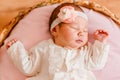 Cute sleeping baby girl in smart white dress and golfs lies on a round crib. photo shoot of newborns Royalty Free Stock Photo