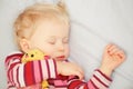 Cute sleeping blond baby with toy