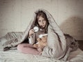 Little girl sitting on bed with teddy bear and alarm clock sleepless at night suffering insomnia