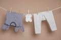 Cute small baby clothes hanging on washing line against brown background Royalty Free Stock Photo