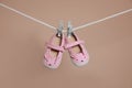 Cute small baby shoes hanging on washing line against brown background Royalty Free Stock Photo