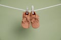 Cute small baby shoes hanging on washing line against green background Royalty Free Stock Photo