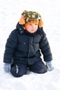 Cute small boy kneeling in winter snow