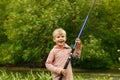 Cute small boy stand near a river with a fishing rod in his hands. Royalty Free Stock Photo