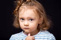 Cute small concentrated kid girl with serious face looking and decided the question on black studio background. Closeup Royalty Free Stock Photo