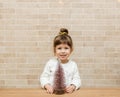 Cute small girl with Christmas tree.Brick wall background.Minimalist style Royalty Free Stock Photo