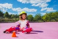 Cute small girl learn to skate rollers, sit in helmet and smile Royalty Free Stock Photo