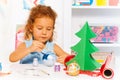 Cute small girl paints New Year ball for Xmas tree