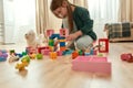 A cute small girl playing with her toys on the floor at home