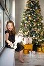 Cute small girl with snowman having fun near Christmas tree indoor. Merry Christmas and Happy New Year