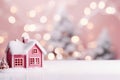 Cute small house Christmas background with copyspace. Festive blush pink snowy landscape with Christmas lights, blurred background Royalty Free Stock Photo