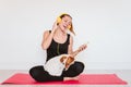 Cute small jack russell dog doing yoga on a mat at home with her owner. Young woman listening to music on yellow mobile phone and Royalty Free Stock Photo