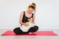 Cute small jack russell dog doing yoga on a mat at home with her owner. Young woman listening to music on yellow mobile phone and Royalty Free Stock Photo