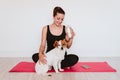 Cute small jack russell dog sitting on a yoga mat at home with her owner woman drinking water. Healthy lifestyle indoors Royalty Free Stock Photo