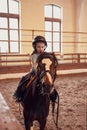 Cute small kid girl learning to ride a horse in farm corral Royalty Free Stock Photo