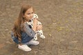 Cute small kid play with toy dog sitting on pebble pavement outdoors, playing, copy space Royalty Free Stock Photo