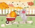 Cute small mouse with a wheelbarrow carrying pumpkins and berries in it. Autumn landscape with a cute mouse.