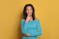 Cute smart mixed race ethnicity black woman in blue shirt thinking on colorful yellow background Royalty Free Stock Photo