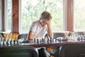 Cute, smart, 11 years old boy in white shirt sits in the classroom and plays chess on the chessboard. Training, lesson, hobby Royalty Free Stock Photo