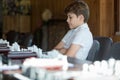 Cute, smart, 11 years old boy in white shirt sits in the classroom and plays chess on the chessboard. Training, lesson, hobby Royalty Free Stock Photo