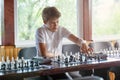 Cute, smart, young boy in white shirt plays chess on the chessboard in the classroom. Education, hobby, training Royalty Free Stock Photo