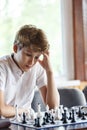 Cute, smart, young boy in white shirt plays chess on the chessboard in the classroom. Education, hobby, training Royalty Free Stock Photo