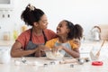 Cute smiling african american mother and daughter cuddling while baking Royalty Free Stock Photo