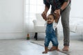 Cute smiling African baby girl learning to walk with father support and holding her hands. Happy toddler child taking first step Royalty Free Stock Photo