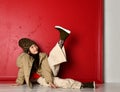 Cute asian kid girl in fashion oversize jacket and wide velvet pants lies on the floor looking at her leg she holds up Royalty Free Stock Photo