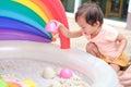 Cute smiling Asian 2 years old toddler girl child playing with kinetic sand in sandbox at home Royalty Free Stock Photo