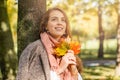 Cute smiling autumn woman holding yellow maple leaf outdoors. Romantic girl in fall park Royalty Free Stock Photo