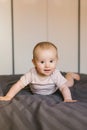 Cute smiling baby boy in bed lying on his belly in bedroom Royalty Free Stock Photo