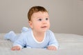 Cute smiling baby boy in bed lying on his belly Royalty Free Stock Photo