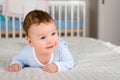 Cute smiling baby boy in bed lying on his belly Royalty Free Stock Photo