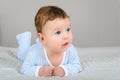 Cute smiling baby boy in bed lying on his belly Royalty Free Stock Photo