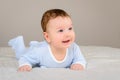 Cute smiling baby boy in bed lying on his belly Royalty Free Stock Photo