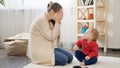 Cute smiling baby boy playing hide and seek with his mother sitting on carpet. Baby development, family playing games, having fun Royalty Free Stock Photo