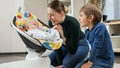 Cute smiling baby boy rocking in chair and looking at mother ond older brother. Child development and happy childhood