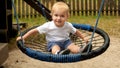 Cute smiling baby boy swinging in rope swing. Kids playing outdoors, children having fun, summer vacation Royalty Free Stock Photo